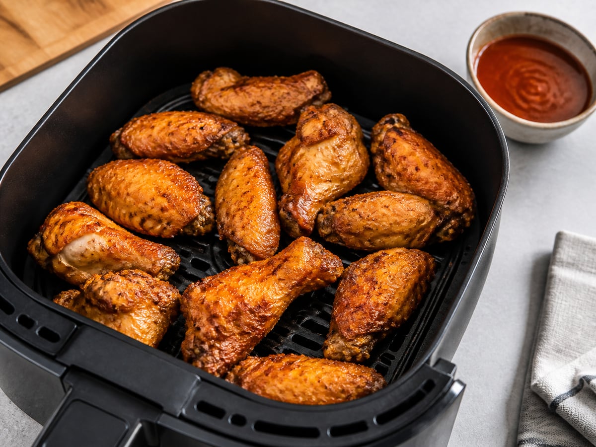 Air fryer basket with cooked chicken wings